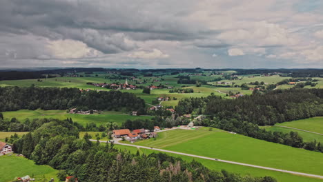 drone shot on a cloudy day of fresh meadows and small viallges in allgäu, germany