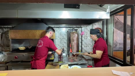 ankara, two men working in front of a doner stick, doner master is cutting the meat from the doner stick and the other man is weighting and preparing the doner kebab plates for customers.