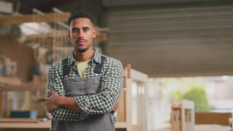 portrait of serious male apprentice working as carpenter in furniture workshop