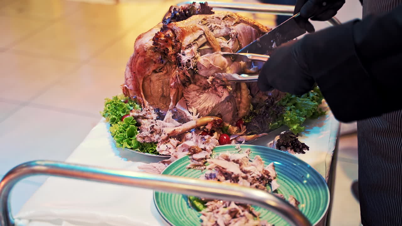 Waiter cutting chicken for guests. Waiter puts on plate to client a piece of fresh fried chicken