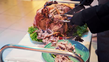 waiter cutting chicken for guests. waiter puts on plate to client a piece of fresh fried chicken