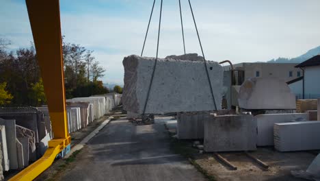 gran grúa amarilla que mueve una enorme roca de mármol en una fábrica de mármol