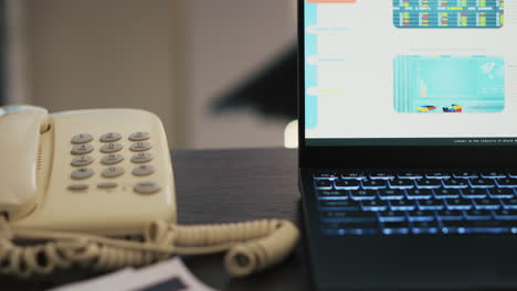 report on desk next to phone and laptop showing stock market diagrams, close up