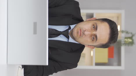vertical video of home office worker man looking at camera depressed.