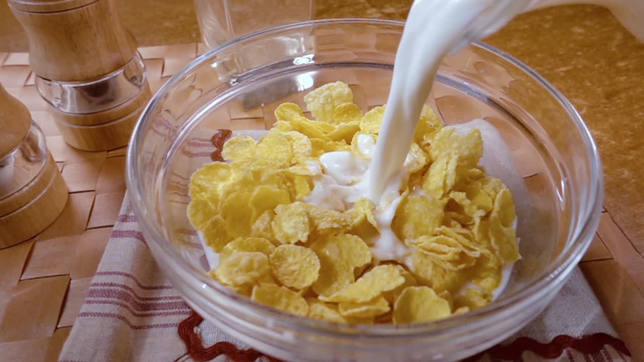 Knusprige gelbe Cornflakes in die Schale für ein köstliches Frühstück mit Milch am Morgen. Zeitlupe mit rotierender Kamerafahrt