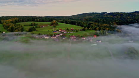 thick layer of misty fog clouds spread across mountainous village homes on terraced fields in the forest