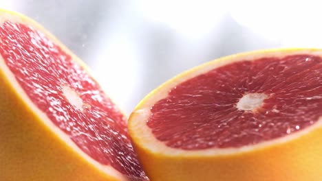 water spraying particles falling on sliced grapefruit surface in slow motion, extreme close-up