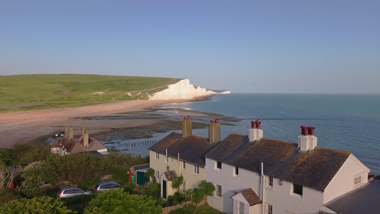 Drone glides past the white cliffs of Seven Sisters, revealing the Coastguard Cottages perfectly placed at a dramatic coastal edge