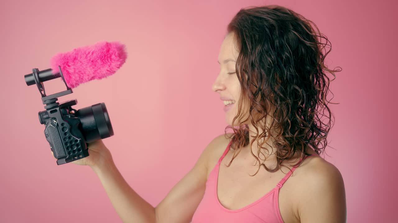 Mujer grabando un video con un micrófono rosa y una cámara