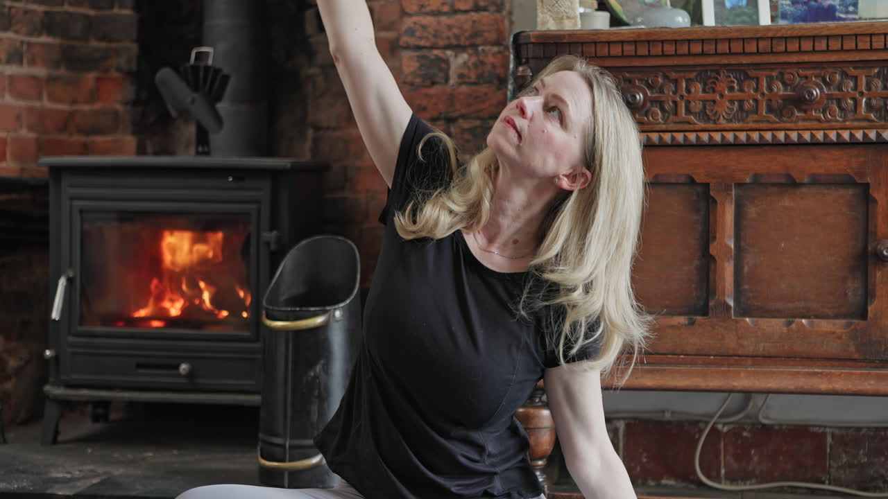 Woman doing yoga indoors by fireplace