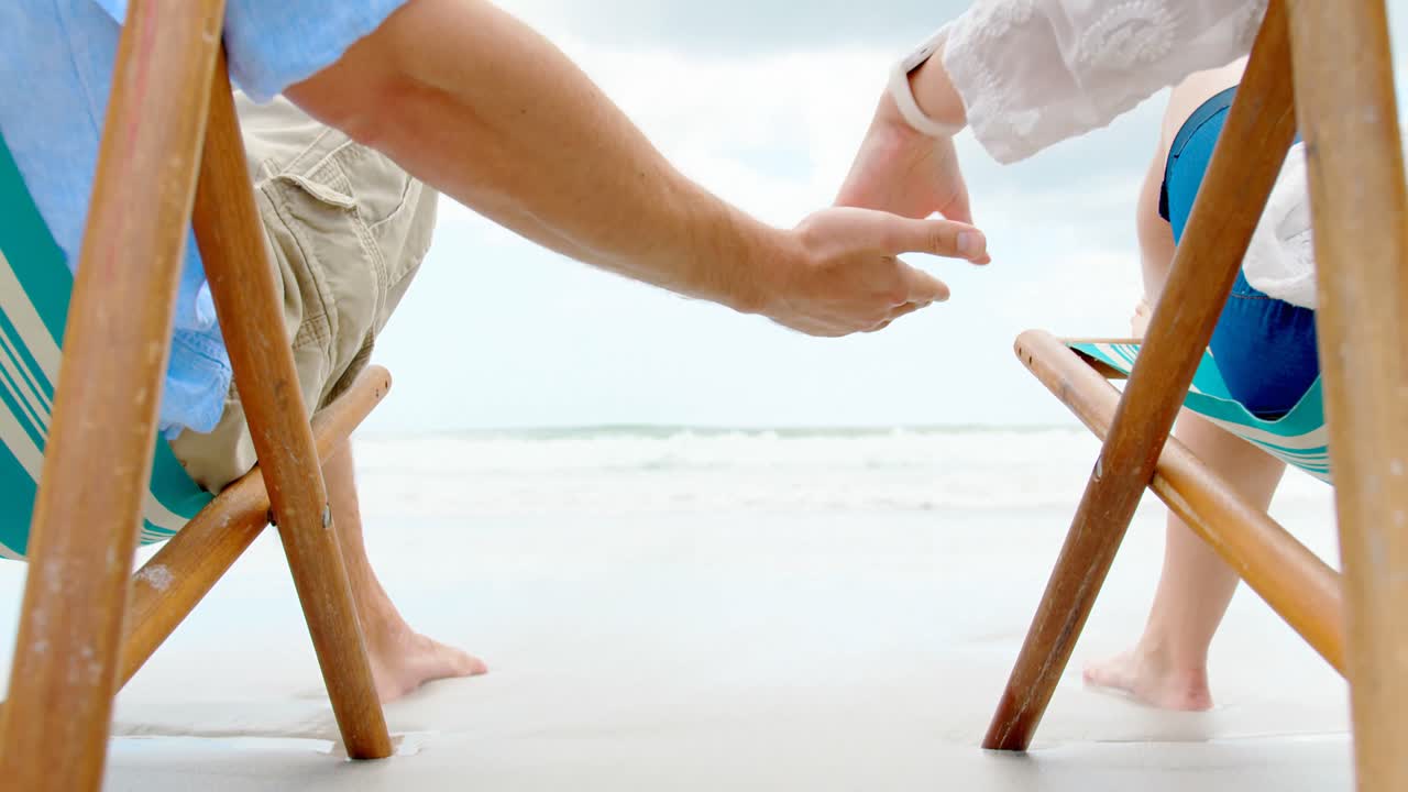 ⁇ 은 날 해변에서  ⁇ 자리에 손을 잡고 있는 커플의 중간 섹션 4k