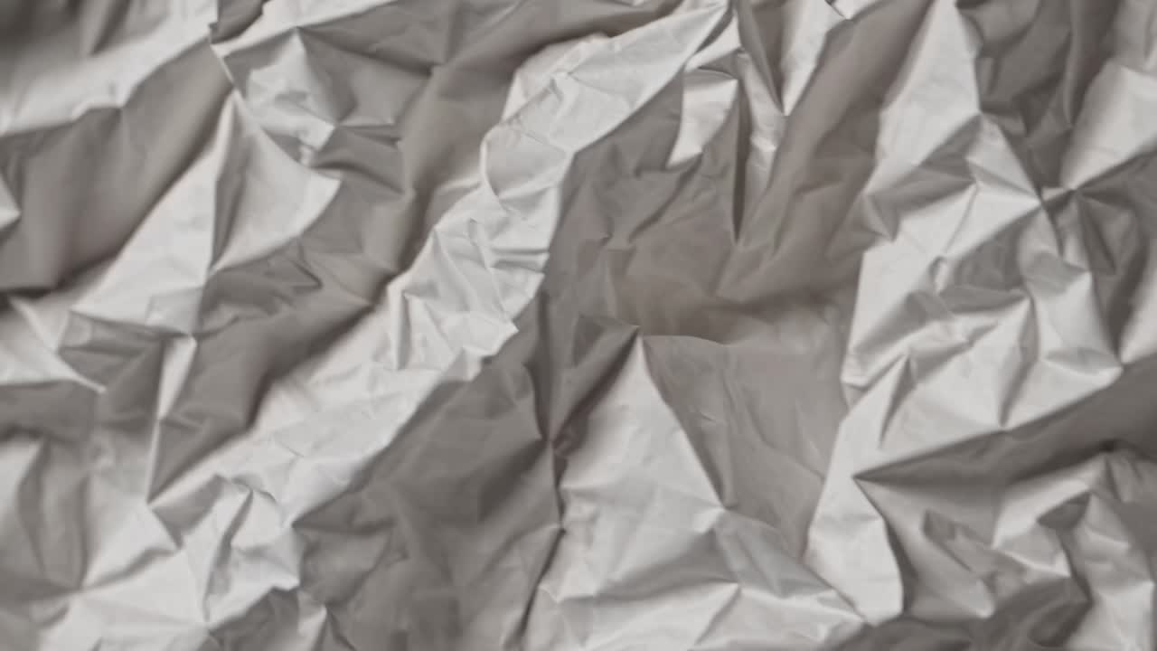 Close-up, top-down view of crumpled silver paper, creating an abstract texture