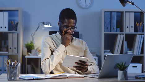 Nahaufnahme-Eines-Geschäftsmannes-Mit-Brille,-Der-Sich-Etwas-Auf-Dem-Tablet-Ansieht-Und-Nachts-Im-Büro-Auf-Den-Bildschirm-Klebt-1