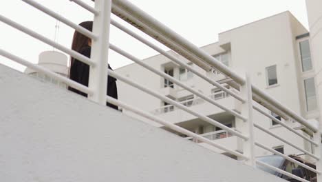 Pretty-girl-with-bron-hair-is-coming-to-white-fence-rail-leaning-over-to-look-around-then-relax-on-the-fence-to-look-at-the-sunset-partly-cloudy-weather-spanish-looking-environment-scenery-slow-motion