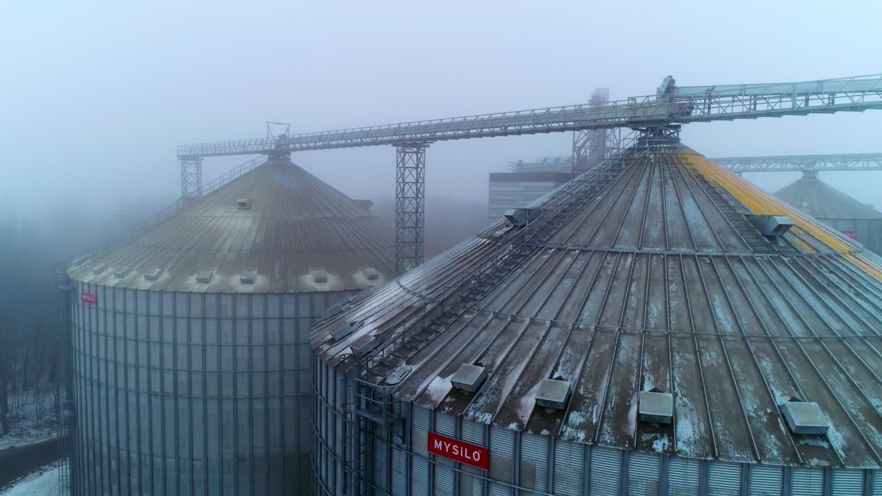 Elevator tanks for storage and processing crops. Huge silo tanks shot in foggy weather. Misty background.