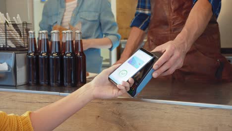 young woman is using contactless nfc payment app installed on her smartphone to pay for gourme street food. eco friendly gluten free food court selling modern fusion cuisine