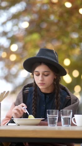 young woman eating soup outdoors