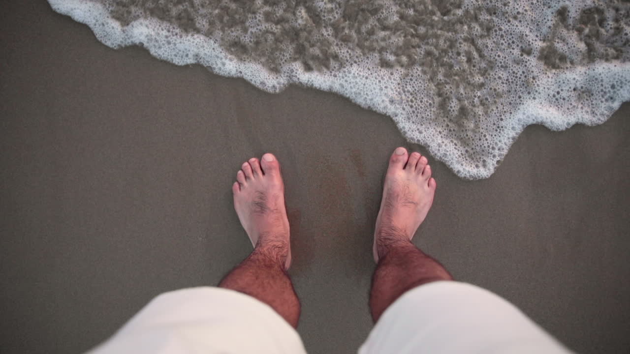 Satisfying view of feet in the sand caressed by a wave
