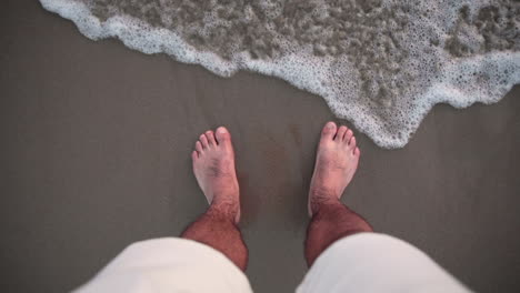 satisfying view of feet in the sand caressed by a wave