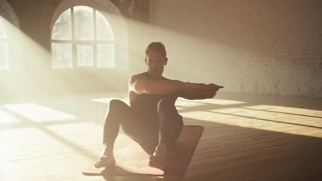 Man-in-sportswear-summer-uniform-waving-his-arms-from-left-to-right-and-pumps-the-abdominal-muscles-on-a-special-mat-in-a-sunny