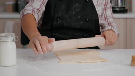 closeup of child hands preparing homemade dough using rolling pin