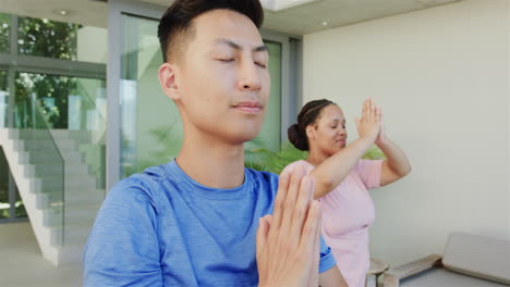 un joven asiático y una joven de dos razas practican yoga al aire libre.