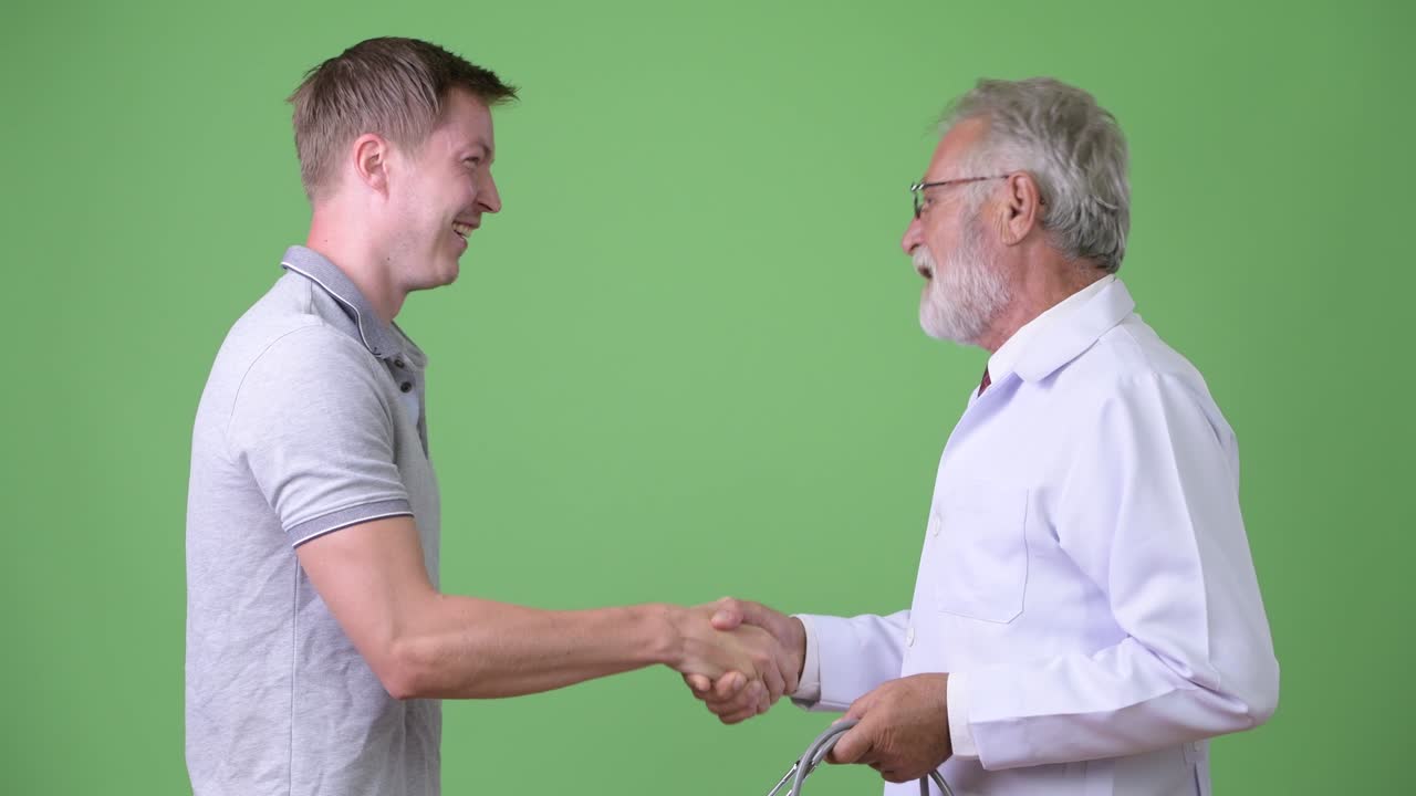 anciano barbudo médico consultando hombre paciente contra fondo verde