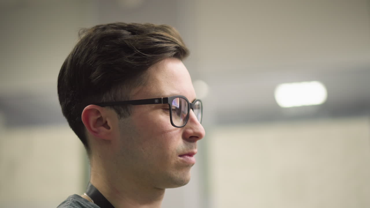 Focused sound engineer working in broadcast control room, adjusting audio levels on mixing desk. Multiple monitors and professional equipment in background for live broadcast or recording session