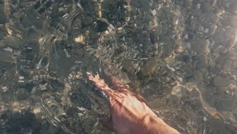 hand touching the waves in slow motion at a rocky beach