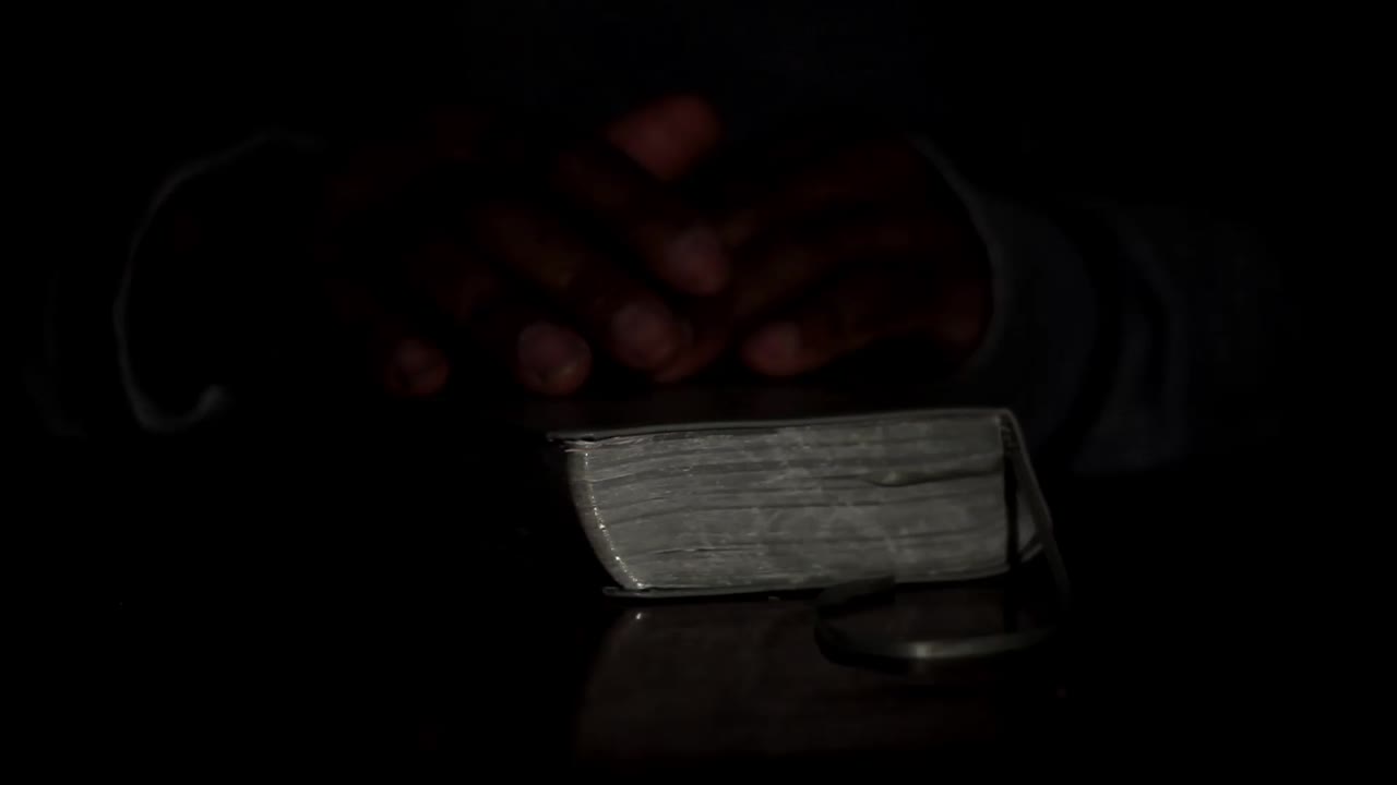 rezando a dios con las manos junto con la biblia y la cruz hombre negro rezando con fondo negro almacen de metraje de archivo