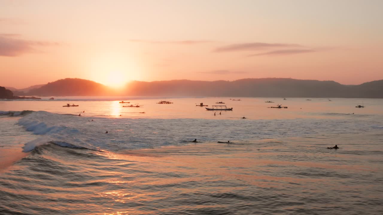 롬복에 있는 게루푹의 서핑 장소에서 일출, 어선과 서퍼가 있는 만의 전망