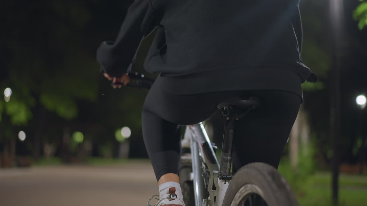 Nighttime Rider On Tranquil Avenue, Serene Cyclist Traveling Quiet City Streets At Dusk, Calm Urban Cyclist Pedaling Steadily Through Illuminated Trees During Peaceful Evening Hours