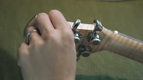 man checking and tuning the guitar by turning the machine heads of an acoustic guitar