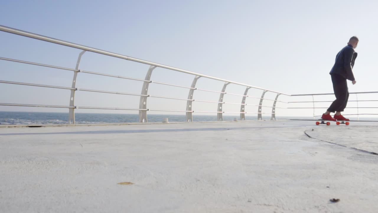 빨간 운동화를 입은 젊은 남자가 바다에서 스케이트를  ⁇ 고 있다.