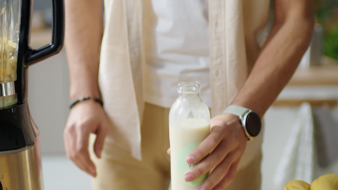 Man Pouring Vegan Milk into Blender with Fruit