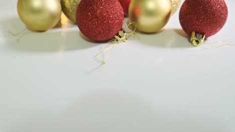 bolas de navidad rojas y doradas decoradas con brillo cerca de la mesa blanca con una guirnalda en el fondo