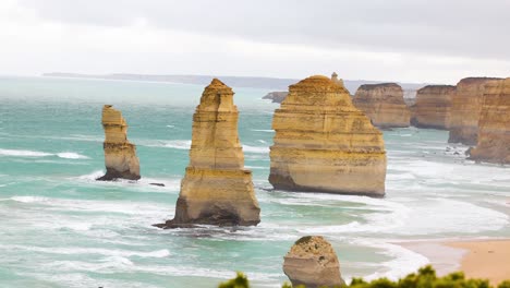 a serene view of the twelve apostles with waves crashing against limestone stacks under overcast skies at port campbell, australia