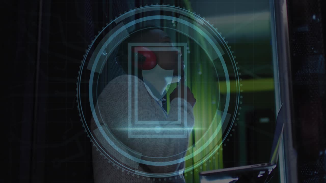 animación del icono del escudo de seguridad sobre un ingeniero afroamericano usando una computadora portátil en la sala del servidor