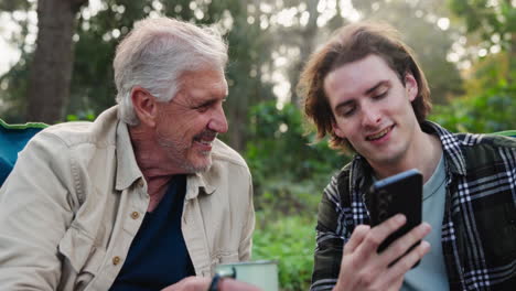 father and son using smartphone outdoors