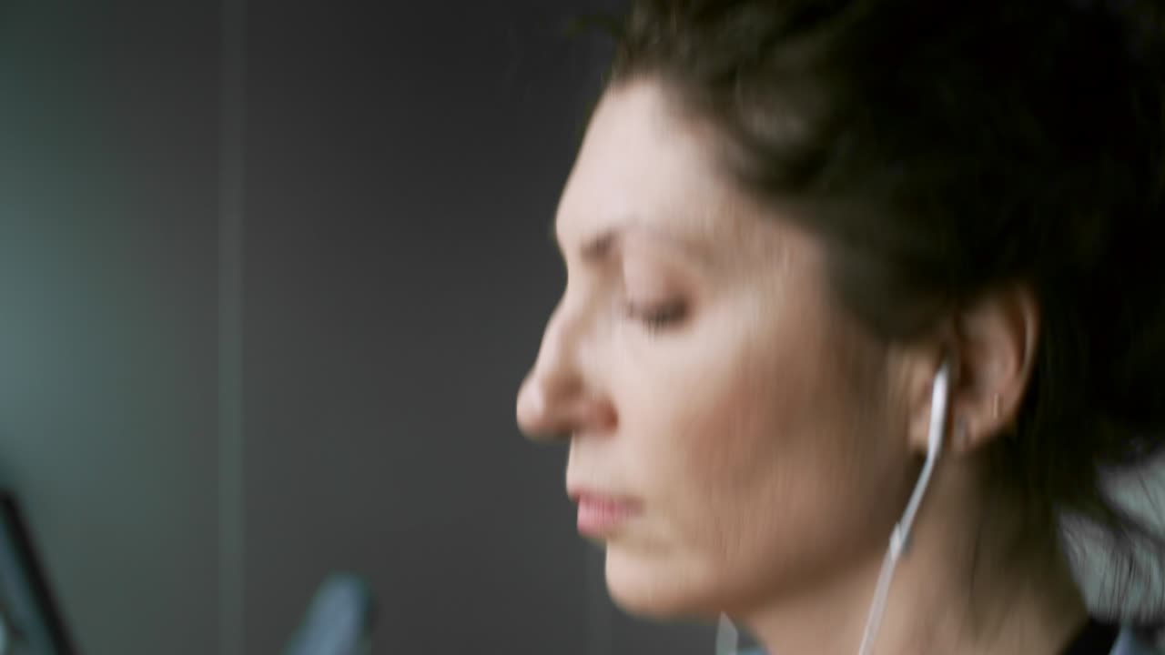 mujer escuchando música mientras hace ejercicio en el gimnasio