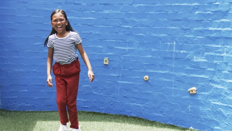 en un patio de escuela, una joven de dos razas sonríe brillantemente, fondo azul con espacio de copia