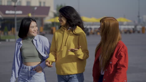 multi ethnic female friends walk and talk together outdoors