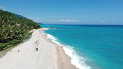 una estrecha playa de guijarros entre el azul profundo del mar caribe y un río alimentado por manantiales de agua dulce en la costa de la república dominicana en los patos