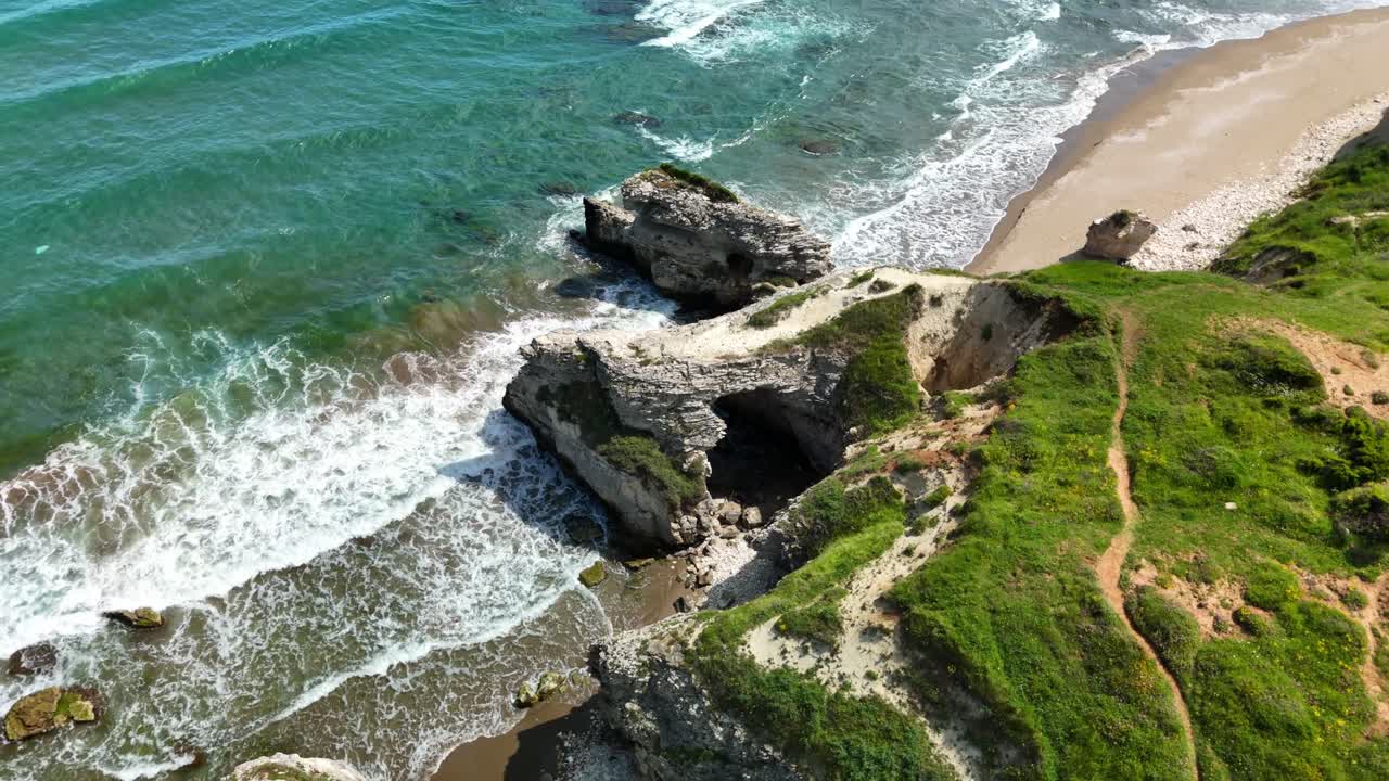 Drone view of rugged coastline with waves hitting rocky cliffs