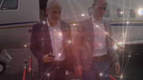 Animation-of-network-of-connections-over-caucasian-businessmen-walking-outside-plane