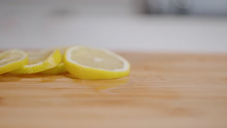 fresh yellow lemon slice spins and falls onto stack of lemons in slow motion