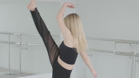 fit girl in black clothes performing contemporary. female dancer shows flowing motions, body and hands waves at white room. modern ballet dance choreography. young woman is moving smoothly