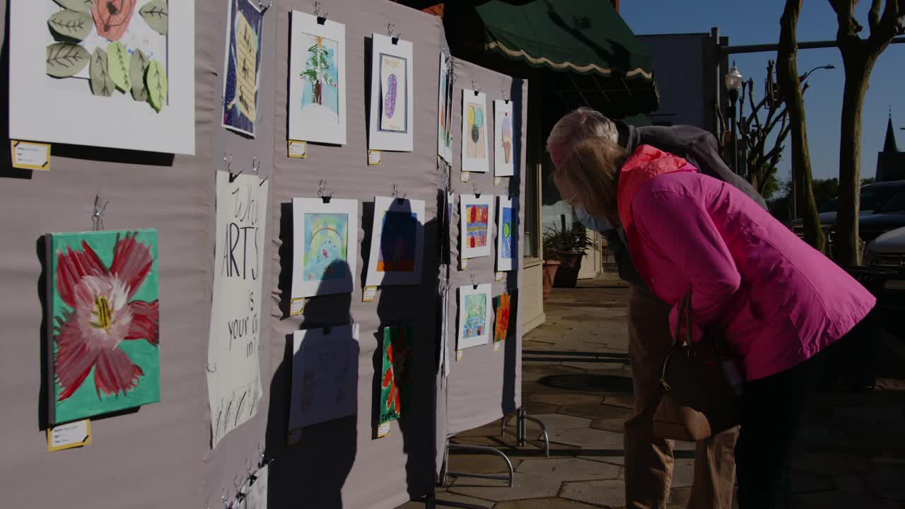 A couple wearing facemasks and face shields admire art at Artsapalooza. Americus First Friday Art Event Sumter County Georgia