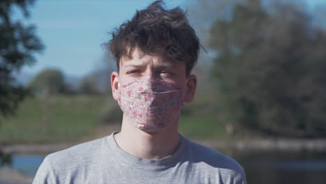 young man puts on homemade flower pattern corona virus cotton mask mid shot