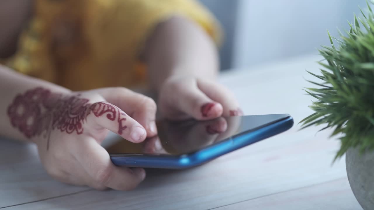 Bambino che usa un telefono cellulare con disegno all'henné sulle mani